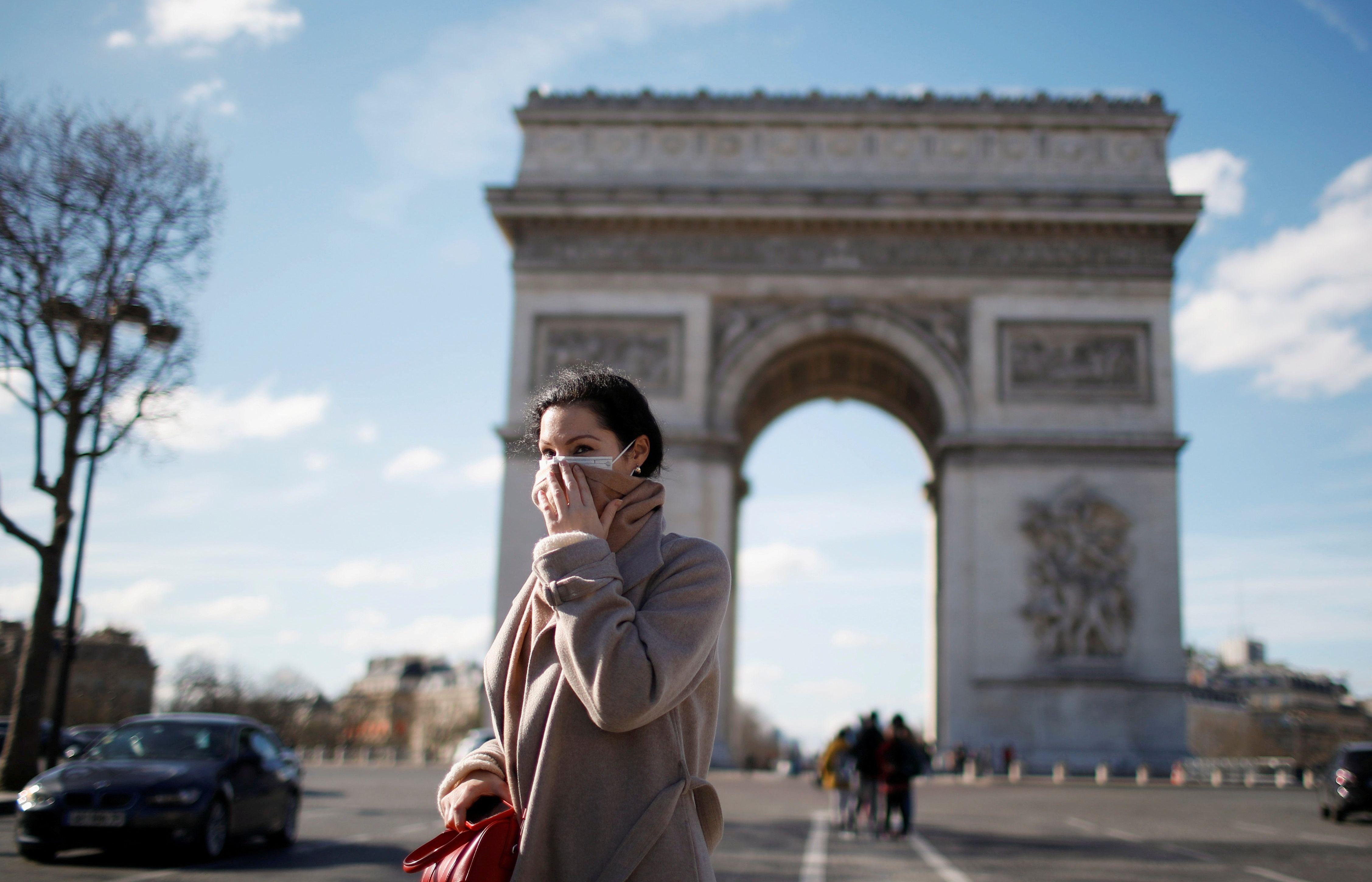 Una mujer que usa una máscara protectora contra el coronavirus camina cerca del Arco del Triunfo en París, Francia. (REUTERS / Gonzalo Fuentes).