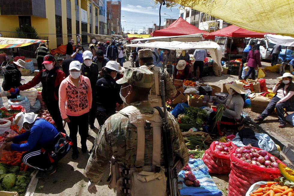 Soldiers patrol as residents attend a street market in Puno, Peru, near the border with Bolivia, on May 1, 2020, despite the regulation to avoid crowded events to prevent the spread of the new coronavirus. - The government has identified markets as major hotspots of the COVID-19 virus. 40,459 cases of coronavirus and 1,124 casualties were confirmed in Peru so far. (Photo by Juan Carlos CISNEROS / AFP)