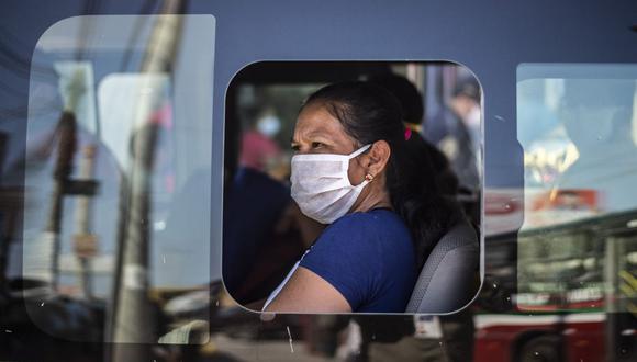 Una mujer con una mascarilla en una unidad de transporte público fuera del mercado de Ciudad de Dios, en Lima (Foto: ERNESTO BENAVIDES / AFP)