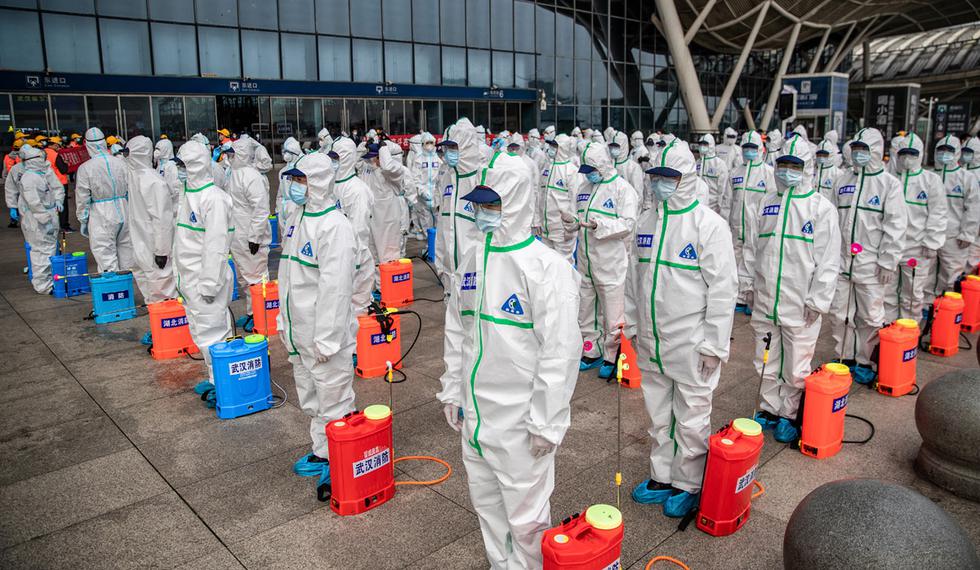 Miembros del personal hacen fila mientras se preparan para rociar desinfectante en la estación de tren de Wuhan en Wuhan, en la provincia central china de Hubei. (Foto: AFP/China OUT)
