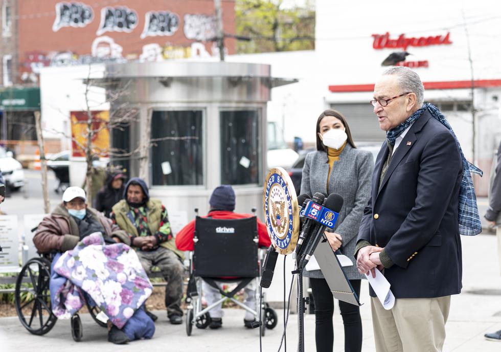 Senate Minority Leader Chuck Schumer speaks as Democratic Congresswoman from New York Alexandria Ocasio-Cortez wearing a face mask to protect herself from the coronavirus, listens during a press conference in the Corona neighbourhood of Queens on April 14, 2020 in New York City. - Senate Minority Leader Chuck Schumer and Democratic Rep. Alexandria Ocasio-Cortez hold a press conference amid the coronavirus pandemic to call on the Federal Emergency Management Administration (FEMA) to begin approving disaster funds to help families in lower-income communities and communities of color pay for funeral costs. (Photo by Johannes EISELE / AFP)