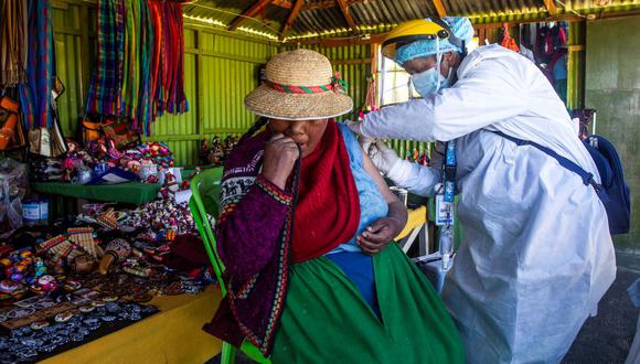 Brigadas de salud también acuden ahora a vacunar a casas y lugares de trabajo, como el caso de esta habitante de las islas flotantes Los Uros en Puno. (Carlos Mamani / AFP).