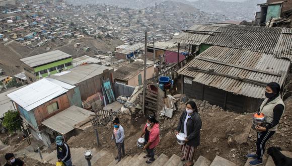 Las mujeres esperan para obtener comida en un comedor comunitario de Pamplona Alta, en Lima, Perú. (Foto por ERNESTO BENAVIDES / AFP).